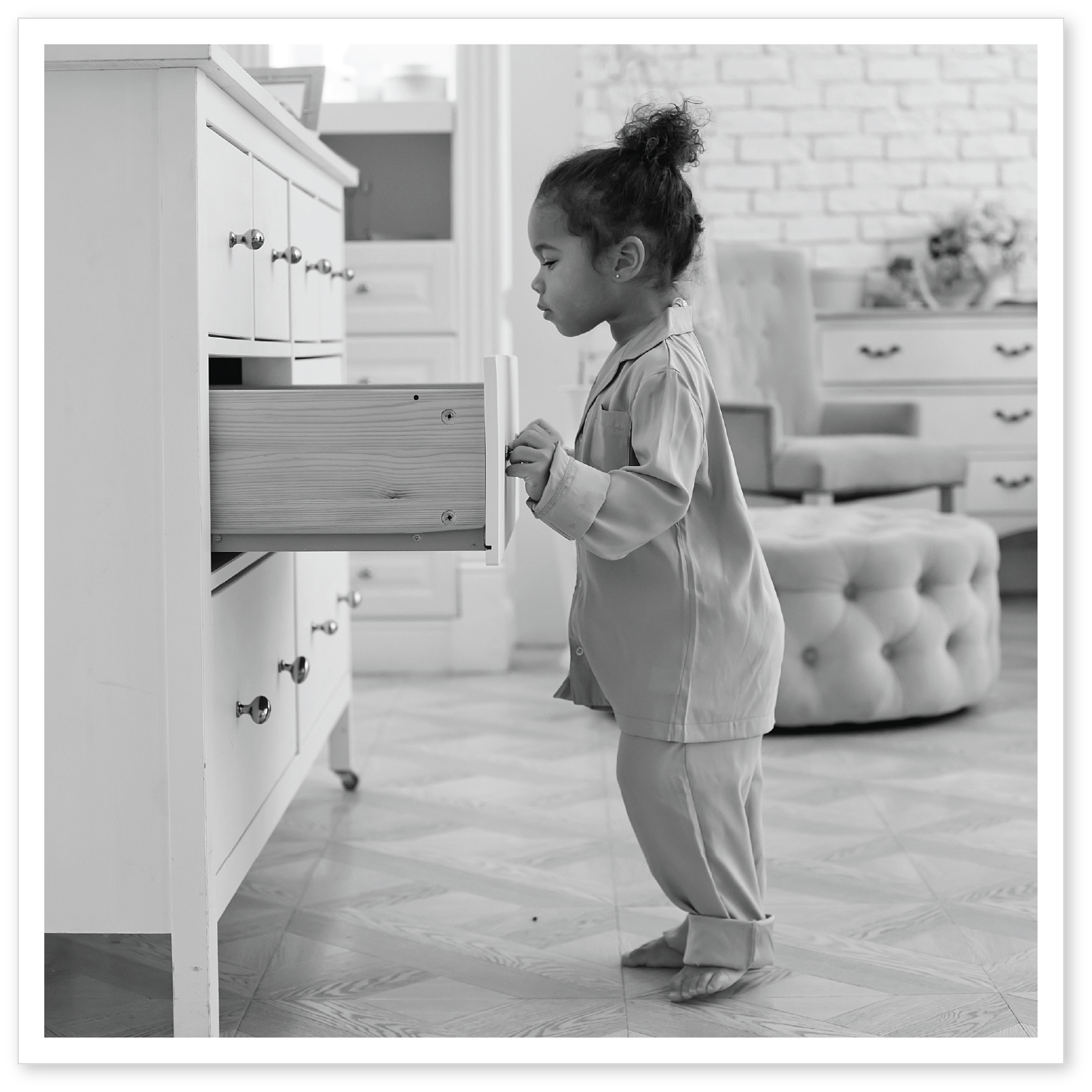 A little girl looks into a drawer in a bedroom.