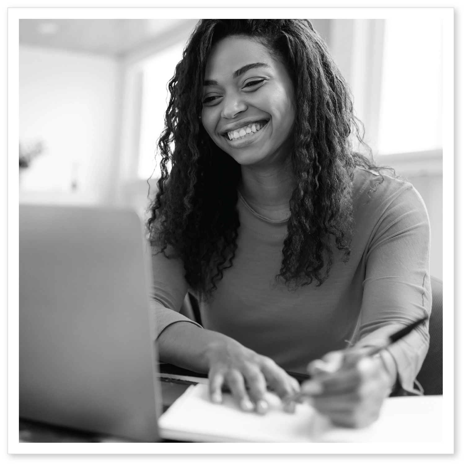 A woman smiling at her laptop during an online workshop